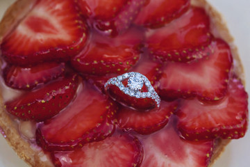 Engagement set of rings on the top of the sweet strawberry cake