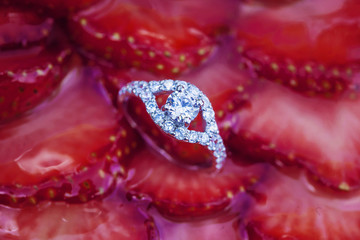 Engagement set of rings on the top of the sweet strawberry cake