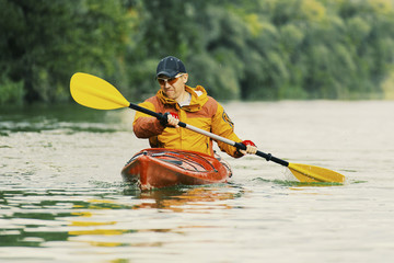 Canoeing. A man is rowing along the river.