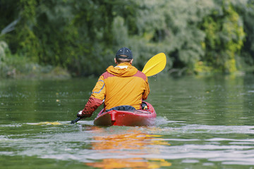 Canoeing. A man is rowing along the river.