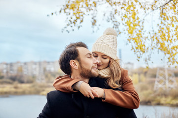 Fototapeta premium Loving couple walking in Park in autumn hugs and kisses. Autumn walk men and women in the woods on the fallen leaves. Romance and love on an autumn landscape