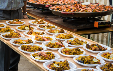 Distribution of the finished giant paella. Plates with paella are put on huge plywood trays for transportation to the table.