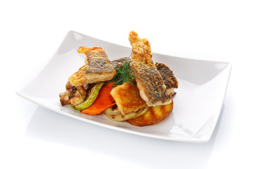 Fried fish with vegetables on a plate. Isolated on white