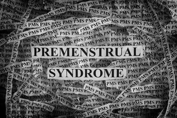 Torn pieces of paper with words Premenstrual Syndrome