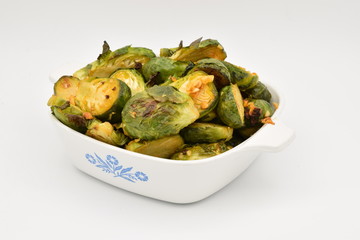 Roasted Brussel Sprouts in a white ceramic dish on a white background