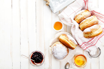 Tea time with festive sufganiyot donuts filled with jelly and covered with sugar powder. White...