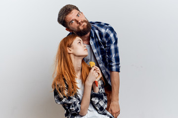 Beautiful young woman on a light background with a man with a beard holding building tools for repair