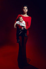mother in red long dress at the studio with a baby boy
