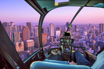 Fototapeta na wymiar Helicopter cockpit inside the cabin flying on buildings in the middle of Osaka with spectacular magenta sunset. Umeda district aerial view. Osaka cityscape, Japan.