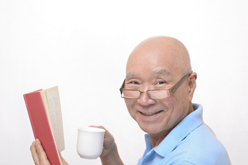 コーヒーを飲みながら読書をするシニア
