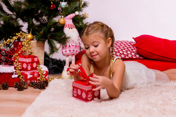Cute little girl with her festive gift near Christmas tree