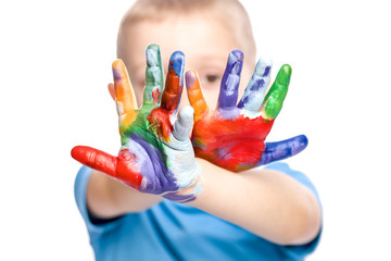 portrait of a 4 year old caucasian boy with unevenly colored hands with acrylic paints. concept of creativity, fun and carefree.