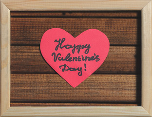 Cut out of red paper hearts on wooden background in wooden frame, greetings happy Valentine's day top view