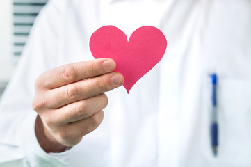 Doctor holding red heart. High blood pressure, heart attack or disease concept.