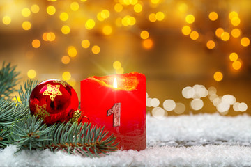 Erster Advent, Adventsdekoration, Kerze, Kugel  und Tanne im Schnee vor Bokeh 