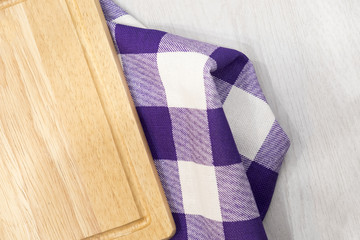 Cutting board over towel on wooden kitchen table. Kitchen purple plaid color kitchen cloth. Food decoration.Textile on a gray background. mockup, Top view. flat lay. copy space for text