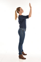 Full length portrait of a girl wearing simple blue shirt and jeans, standing pose side profile, on...