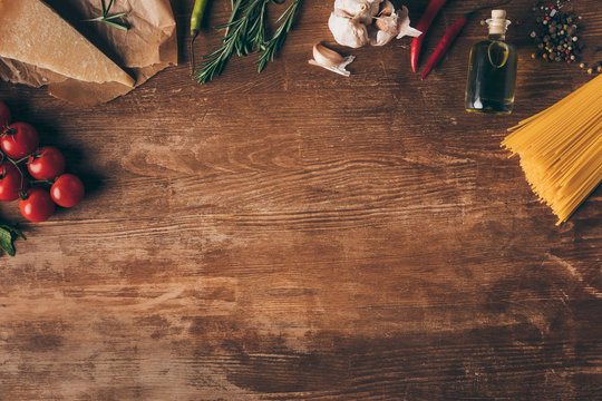 Top View Of Row Pasta And Fresh Ingredients On Wooden Table With Copy Space