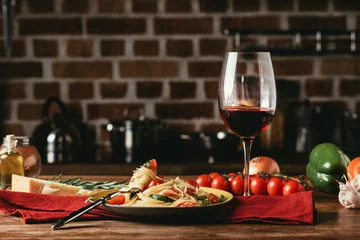 Keuken spatwand met foto traditional italian pasta with tomatoes and arugula in plate and glass of red wine © LIGHTFIELD STUDIOS