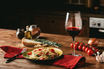 traditional italian pasta with tomatoes and arugula in plate and glass of red wine