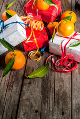 Christmas and New Year concept. Fresh Tangerines with green leaves in a white basket, Christmas decoration and gift boxes, on old rustic wooden table, copy space