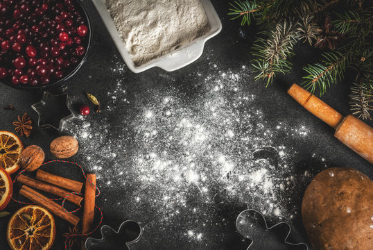 Ingredients for Christmas, winter baking cookies. Gingerbread, fruitcake. Flour, cranberries, dried oranges, cinnamon, spices on a black stone table, top view copy space