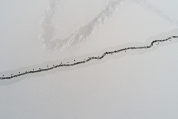 Drone view on winter lake with cracked ice
