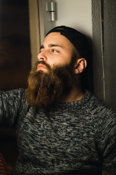 Bearded man in cap posing inside