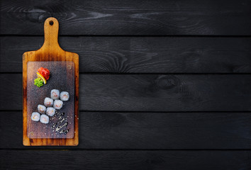 Classic sushi roll with shrimp on a wooden board. Top view. Black wooden background