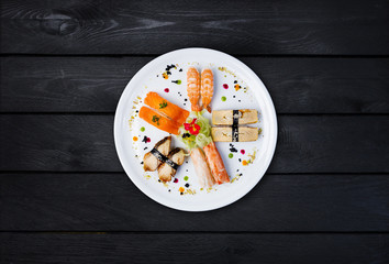 Sashimi set on a white round plate, decorated with small flowers, Japanese food, top view. Black...