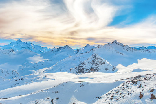 Fototapeta Mountains with snow peaks and sunset sky