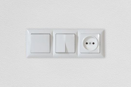Electric light switch and socket on the empty wall, electrical power socket and plug switched
