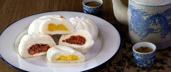 Steam stuff Buns (Sa La Pao) Stuffed red pork chop and Cream Chinese snack with Chinese pot tea in dim light on wooden background