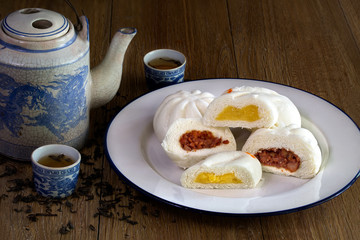 Steam stuff Buns (Sa La Pao) Stuffed red pork chop and Cream Chinese snack with Chinese pot tea in dim light on wooden background