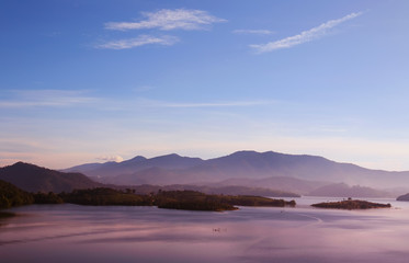 beautiful landscape with the surface of the sea with mountains in the background in the pink dawn