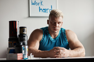 Strong bodybuilder sitting at the table