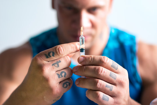 Close up of a syringe in hands of a bodybuilder