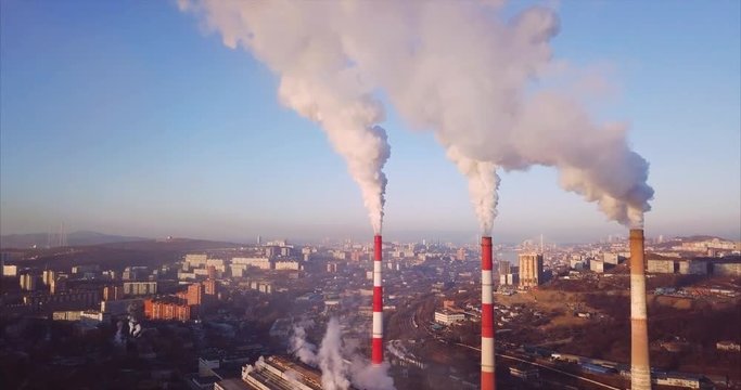 Beautiful aerial view of three high Central Heating and Power Plant chimneys with steam rising from them. Vladivostok is on the background, Russia. Sunrise