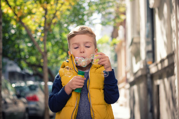 Little boy blowing bubbles with bubble wand.