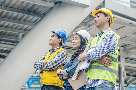 Mature engineers people in hard hats looking up at the site