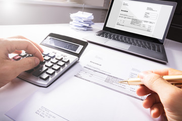 Businessperson's Hand Calculating Invoice