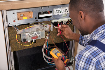 Technician Fixing Dishwasher With Digital Multimeter