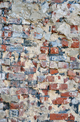 old decaying brick wall with repairs and crumbling cement layer