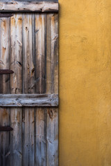 Old wooden door on yellow concrete wall