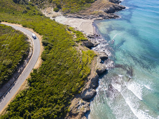 Vista aerea della costa della Corsica, strade serpeggianti e calette con mare cristallino. Penisola...