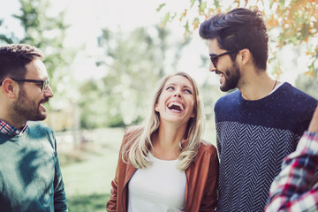 Naklejka premium Image of four happy smiling young friends walking outdoors in the park. Love, happiness and friendship concept
