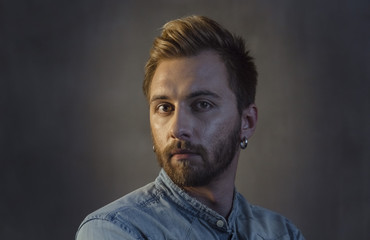 Portrait of bearded man face with stylish hairstyle on head and earring in ear