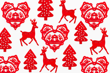 Pattern with red wooden heart with silhouette of house, deer and fir tree. Ornamental red Christmas and New Year decoration. Top view, flat lay on white background.