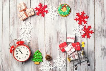 Christmas sale background. Mini cart , gift boxes, christmas gingerbread, snowflackes, red clock on wooden table. View from above. Flat lay. Space for text.