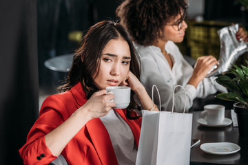depressed young woman drinking coffee after shopping